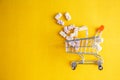 Baby vitamins in the form of bears fell out of the toy carts for products. On a bright yellow background. Pharmaceutical concept Royalty Free Stock Photo