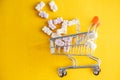 Baby vitamins in the form of bears fell out of the toy carts for products. On a bright yellow background. Pharmaceutical concept Royalty Free Stock Photo