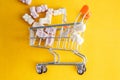 Baby vitamins in the form of bears fell out of the toy carts for products. On a bright yellow background. Pharmaceutical concept Royalty Free Stock Photo