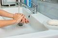 Baby washes soap from hands in washbasin