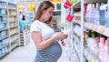 Baby washing powder pregnant woman buying. Young pregnancy woman buy on baby powder detergent on supermarket background Royalty Free Stock Photo