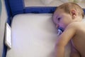 Baby watching a lullaby cartoons with mobile phone on the crib