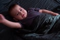 Baby Waving in Bed with Dark Blanket Royalty Free Stock Photo