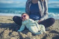 Baby wearing sunglasses on the beach with his mother Royalty Free Stock Photo