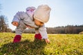 Baby wearing warm beanie hat, sweatshirt and red boots outdoors in rural area discovering nature in spring, sunny day Royalty Free Stock Photo