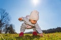 Baby wearing warm beanie hat, sweatshirt and red boots outdoors in rural area discovering nature in spring, sunny day Royalty Free Stock Photo