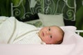 A baby in a white blanket lies on the bed at home and looks into the frame. The concept of childhood, home birth, new Royalty Free Stock Photo