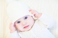 Baby in a white knitted sweater and hat on a white cable knit blanket Royalty Free Stock Photo