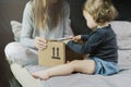 Baby and woman sitting on bed and opening a mail box with products ordered on Internet Royalty Free Stock Photo