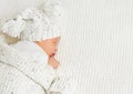 Baby in Woolen Hat with Pompon sleeping on knitted White Blanket. Newborn lying down on Stomach. Infant Child Health Care and Royalty Free Stock Photo