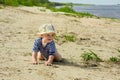 baby 1 year old plays on a sandy beach by the river on a sunny day Royalty Free Stock Photo