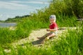 baby 1 year old plays on a sandy beach by the river on a sunny day Royalty Free Stock Photo