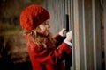 Baby 3 years with long hair.In a red beret and coat stands on the street in the sunshine, near the fence Royalty Free Stock Photo