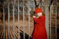 Baby 3 years with long hair.In a red beret and coat stands on the street in the sunshine, near the fence Royalty Free Stock Photo