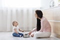 Baby and young mother playing music on kitchen floor Royalty Free Stock Photo