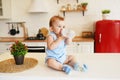 Babyboy sitting on the table in the kitchen and drinking from baby bottle