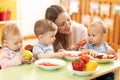 Babysitter feeding nursery babies. Toddlers eat healthy food in daycare