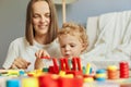 Exploring together in the nursery. Happy family leisure time. Joyful mother playing with little baby