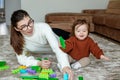 Mother plays with baby in living room on mat. Together they play with colored blocks Royalty Free Stock Photo