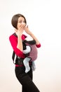 Babywearing attractive young mother with baby in wrong carrier. Isolated on white