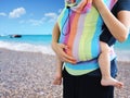 Babywearing practice with mother carrying baby in SSC soft structured carrier on seaside Royalty Free Stock Photo