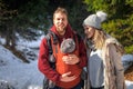 Babywearing winter forest walk with family and their baby son in ergonomic carrier