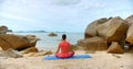 Bach shot of a woman, she seats in meditation pose by the sea line on blue yoga mat