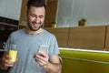 Bachelor man daily routine in a kitchen single lifestyle concept drinking juice and using smartphone Royalty Free Stock Photo