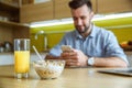 Bachelor man daily routine in the kitchen single lifestyle concept using smartphone during breakfast Royalty Free Stock Photo