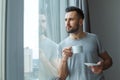 Bachelor man daily routine standing near the window single lifestyle concept drinking coffee thinking Royalty Free Stock Photo