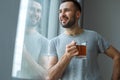 Bachelor man daily routine standing near the window single lifestyle concept drinking tea dreaming Royalty Free Stock Photo