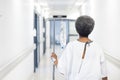 Back of african american senior female patient with drip walking in hospital corridor Royalty Free Stock Photo