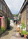 A back alley between streets with rows of traditional stone houses in hebden bridge west yorkshire with washing drying on lines Royalty Free Stock Photo
