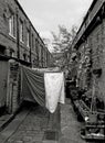 Back alley of traditional british terraced houses with washing on lines and plants in pots taken in hebden bridge