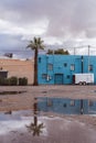 Back area of old colorful buildings in an alleyway with a trailer. Palm tree reflected in puddle after an Arizona rainstorm Royalty Free Stock Photo