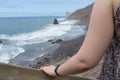 Back Arm of a relaxing girl, holding wood stairs going down to Benijo Beach in Tenerife, wearing a dress. Stand lady explore a