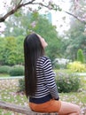 Back of Asian woman sitting on wood bench in the garden outdoor with looking up Royalty Free Stock Photo