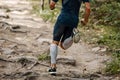 back athlete runner in compression sleeves on his feet running forest trail