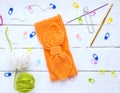 Back background for needlewomen, orange knitted headband for girls