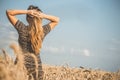 Back of beautiful young woman enjoying nature, raising hands on background of cloudy sky in wheat field, girl raise hands and Royalty Free Stock Photo
