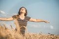 Back of beautiful young woman enjoying nature, raising hands on background of cloudy sky in wheat field, girl raise hands and Royalty Free Stock Photo