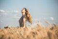 Back of beautiful young woman enjoying nature, raising hands on background of cloudy sky in wheat field, girl raise hands and Royalty Free Stock Photo