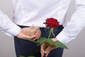 Back behind rear view photo of happy romantic charming handsome gentleman hiding beautiful rose and small package isolated grey