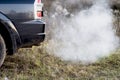 The back of the black car with the emission of smoke from the exhaust pipe on the background of nature Royalty Free Stock Photo