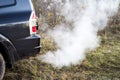 The back of the black car with the emission of smoke from the exhaust pipe on the background of nature Royalty Free Stock Photo