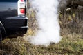 The back of the black car with the emission of smoke from the exhaust pipe on the background of nature Royalty Free Stock Photo