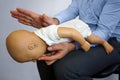 Back blows the Heimlich maneuver or Heimlich manoeuvre on a simulation mannequin infant dummy during medical training Basic Life