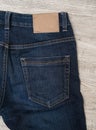 Back of blue jeans on wood background with brown leather label. Royalty Free Stock Photo