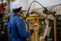 Back of blue uniform technician or worker man control and check the robot working in factory Royalty Free Stock Photo