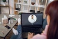 Back blur view of young woman, sitting on couch at home, using her laptop to get medical consultation online from Indian Royalty Free Stock Photo